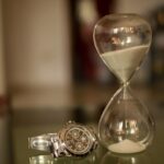Een zandloper en een horloge. De tijd tikt weg en loopt als zand tussen je vingers door.