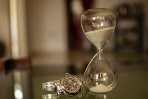 Een zandloper en een horloge. De tijd tikt weg en loopt als zand tussen je vingers door.