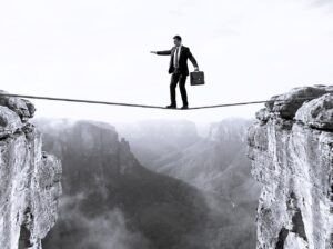 Zakenman balanceert op een strakgespannen koord boven een diepe afgrond. Conceptueel beeld voor het nemen van grote risico's en het zoeken naar financiële of juridische balans.